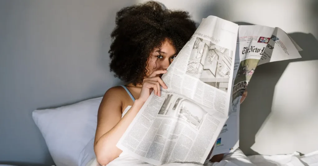 A relaxed morning scene of a woman reading a newspaper in bed, sunlight streaming in.