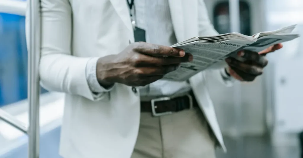 A professional in a blazer reads a newspaper while commuting on a train.